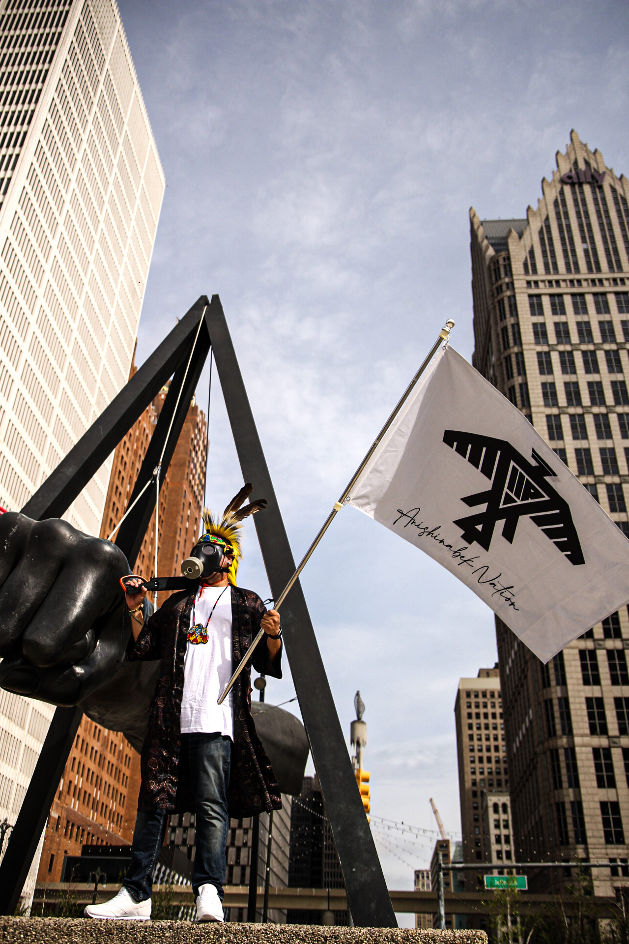 Sacramento Knoxx holding the Anishinabek Nation flag at the Monument to Joe Louis (The Fist) in Detroit